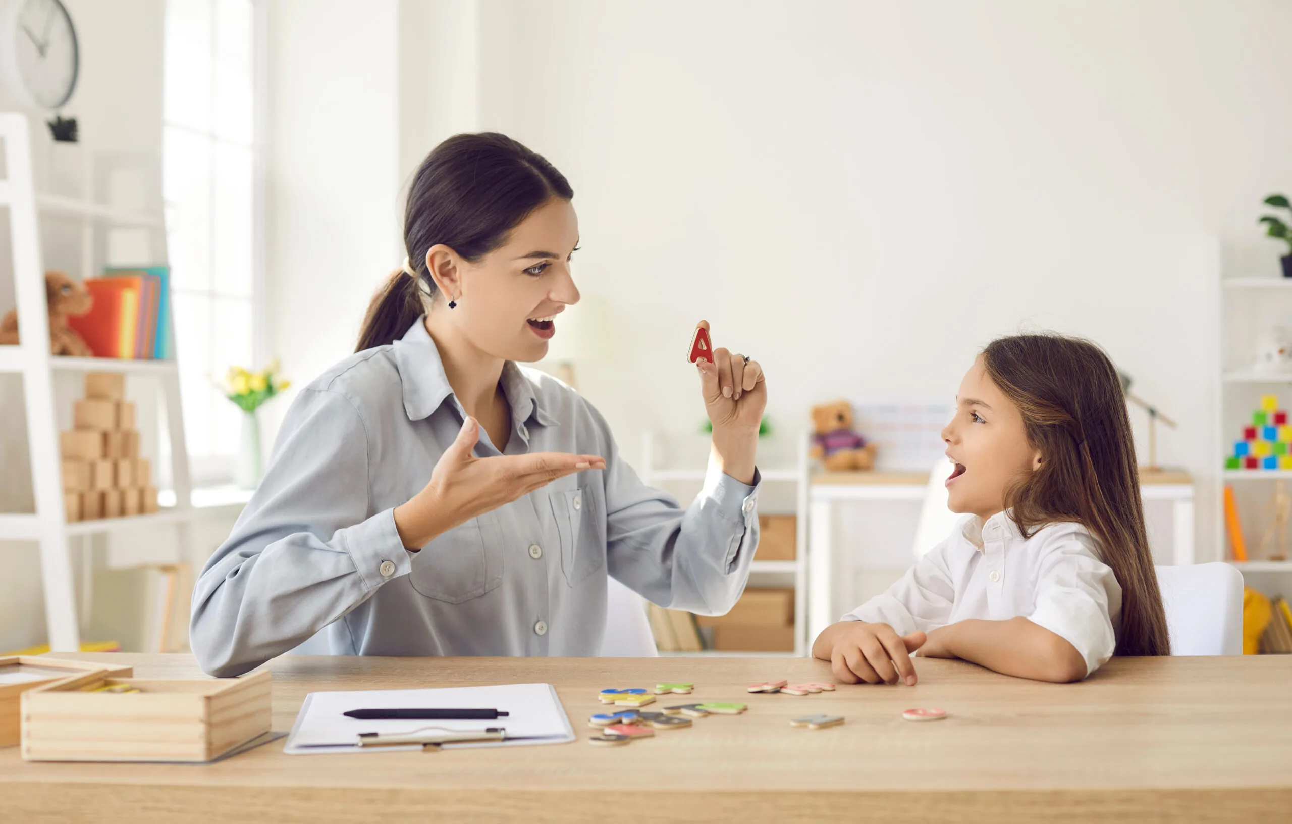 Speech language pathologist helping child learn letters and overcome speech problems